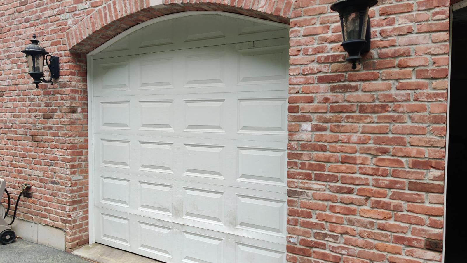 White garage door installed in brick archway on residential home